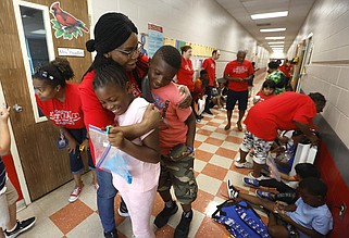 Carver Magnet Elementary second-grade teacher Theresa Ibekwe hugs Destiny Daniels and her brother, Caleb, as they leave the Little Rock school in this June 2, 2023 file photo. June 2, 2023, was the last day of school for the 2022-23 school year in the Little Rock School District. (Arkansas Democrat-Gazette/Thomas Metthe)